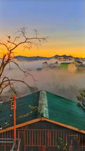 a view of a house in the fog at sunset at Dốc Nhà Tây in Da Lat