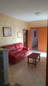 La Dimora del Frappato di Tenute Senia في كيارامونتي غولفي: غرفة معيشة مع أريكة حمراء وطاولة قهوة