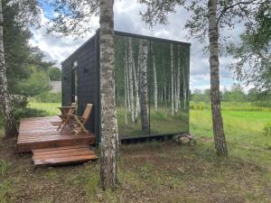 a black house with a wooden deck in the woods at Kuldi Mirror House 