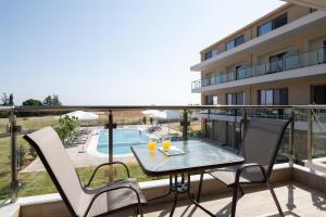 un balcone con tavolo, sedie e piscina di Aetherion Studios & Suites a Kalivia Poligirou