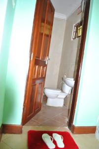 a bathroom with a toilet and a pair of slippers at Ngorongoro Villa and Restaurant in Karatu