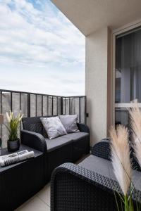 un patio con divano e sedie sul balcone. di Osiedle Avia Harmonious Apartment with Balcony & Parking Cracow by Renters Prestige a Cracovia