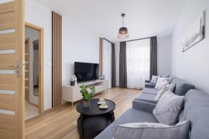 un soggiorno con divano blu e TV di Osiedle Avia Harmonious Apartment with Balcony & Parking Cracow by Renters Prestige a Cracovia