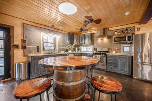 a kitchen with a bar with wooden tables and stools at Hochatown Hot Tub Firepit Arcade Dog Friendly BBQ in Broken Bow