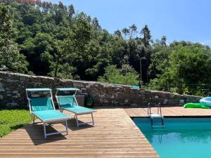 2 sillas sentadas en una terraza junto a una piscina en Podere il Giardino - Casale Rustico degli Ulivi con piscina e parco - Lucca, en Loppeglia