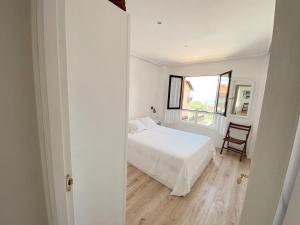 ein weißes Schlafzimmer mit einem Bett und einem Stuhl in der Unterkunft Apartamento Nuria Comillas in Comillas
