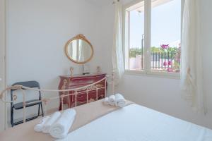 een slaapkamer met een bed, een spiegel en een raam bij Appartamento con vista piscina in Noto +12 foto's