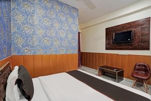 a bedroom with a bed and a tv on a wall at Blue Moon Inn in Greater Noida