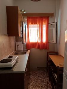 a kitchen with a sink and a window with an orange curtain at Niki Seaside Apartments in Platamonas