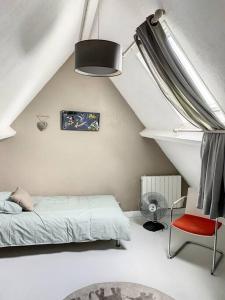 a white bedroom with a bed and a red chair at Le Odette - Campagne chic in Jaux