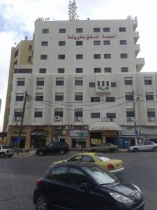 a black car parked in front of a large building at Omaima Hotel Apartments in Amman