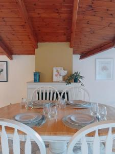 tavolo da pranzo con sedie bianche e soffitto in legno di Doma Menidi Rooftop Apartment a Menídion