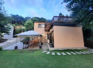 a house with a deck with a table and an umbrella at Clouds Camping House in Nanzhuang