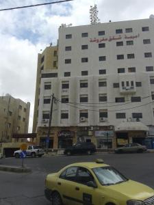 un coche amarillo estacionado frente a un gran edificio en Omaima Hotel Apartments, en Amán
