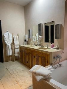 a bathroom with a tub and a sink and mirror at VILLA NAKHLA in Chouiter