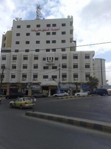 a large white building with cars parked in front of it at Omaima Hotel Apartments in Amman