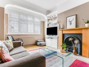 een woonkamer met een open haard en een televisie bij Pass the Keys Stunning 3BR House with Garden Oasis in Londen