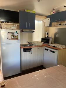 a kitchen with a white refrigerator and a sink at Mobil home 8 personnes camping l elysee in Le Grau-du-Roi