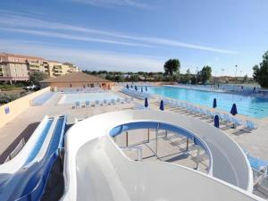 a large swimming pool with chairs and a swimming slide at Mobil home 8 personnes camping l elysee in Le Grau-du-Roi
