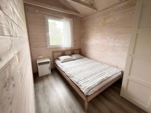 małe łóżko w drewnianym pokoju z oknem w obiekcie Domki Laba w Łebie