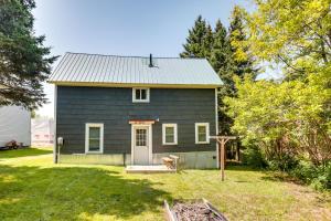 a gray house with a dog in the yard at Pet-Friendly Michigan Getaway with Porch and Kayaks! in Ontonagon