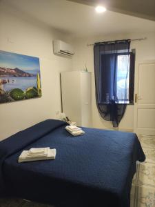 a bedroom with a blue bed and a window at La Casetta di Elia in Lipari