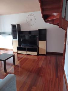 sala de estar con TV y reloj en la pared en Ático duplex, en Santoña