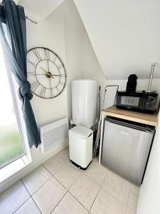 a small kitchen with a clock on the wall at La Topaze Bleue - Romans in Romans-sur-Isère