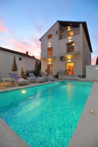 a villa with a swimming pool in front of a house at Apartman Miki Borik in Zadar