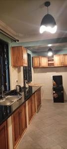 cocina con armarios de madera, fregadero y encimera en Cosy Living, en Gulu