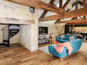 a living room with blue chairs and a brick wall at Tower Barn Cottage in Ryde