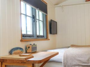een slaapkamer met een bed, een bureau en een raam bij Godrevy Shepherds Hut in Hayle