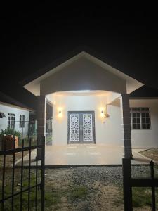 una pequeña casa blanca con una puerta delantera por la noche en Rumah Tamu Zeha Muar Johor, en Muar