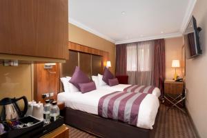 um quarto de hotel com uma cama grande com almofadas roxas em Donnington Manor Hotel em Sevenoaks
