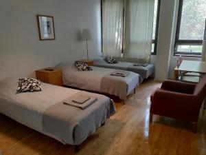 um quarto de hotel com três camas e uma cadeira em Hostel Vekotin em Toijala