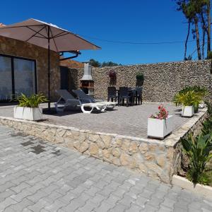 een patio met stoelen, een parasol en een stenen muur bij leiria village casa village in Leiria