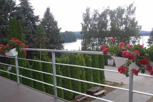 a balcony with flowers on a fence and a river at Hotelik Likusy - przy plaży nad jeziorem Ukiel i z bezpłatnym prywatnym parkingiem in Olsztyn