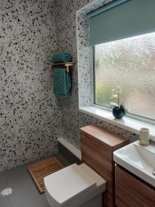 a bathroom with a toilet and a sink and a window at Stunning Views Peaceful Split Level Bungalow in Sutton in Ashfield