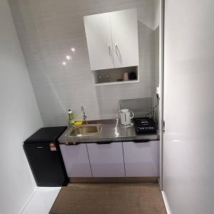 una pequeña cocina con fregadero y armarios blancos en Sky Trees Bukit Indah Nflix Disney Plus Pools Balcony, en Johor Bahru