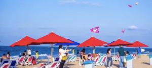 Porto Said Tourist Resort في بورسعيد: مجموعة من الناس على شاطئ به مظلات حمراء
