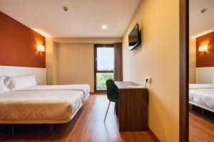 Una habitación de hotel con dos camas y un escritorio. en Checkin Madrid Móstoles, en Móstoles