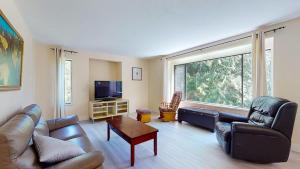 uma sala de estar com mobiliário de couro e uma grande janela em Spacious 3 bedroom house em Gibsons