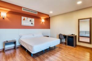 una habitación con una cama, un escritorio y un espejo en Checkin Madrid Móstoles, en Móstoles 26 fotos más