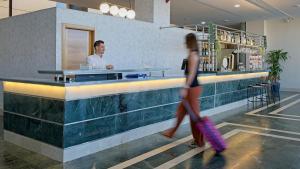 una mujer pasando por un bar con un hombre detrás de un mostrador en Checkin Madrid Móstoles, en Móstoles