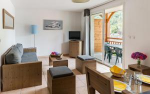 a living room with a table and chairs and a television at Lagrange Vacances Le Belvédère in Saint-Mamet