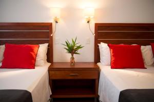 two beds with red pillows in a hotel room at Hotel Saint George in Puerto Iguazú