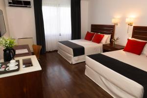 a hotel room with two beds and a table at Hotel Saint George in Puerto Iguazú