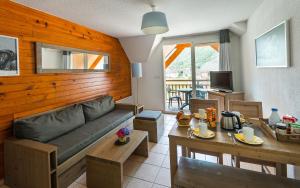 a living room with a couch and a table at Lagrange Vacances Le Belvédère in Saint-Mamet