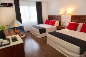 una camera d'albergo con due letti con cuscini rossi di Hotel Saint George a Puerto Iguazú