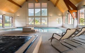 une salle de piscine avec deux chaises et une piscine dans l'établissement Lagrange Vacances Le Belvédère, à Saint-Mamet